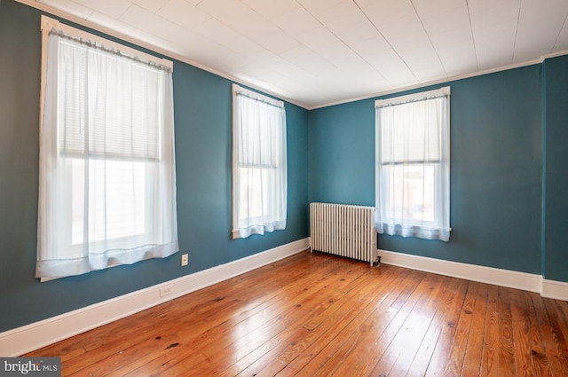 spare room featuring hardwood / wood-style floors, plenty of natural light, radiator heating unit, and ornamental molding