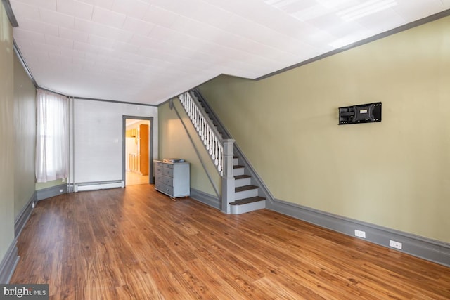 unfurnished living room with ornamental molding, a baseboard radiator, and hardwood / wood-style flooring