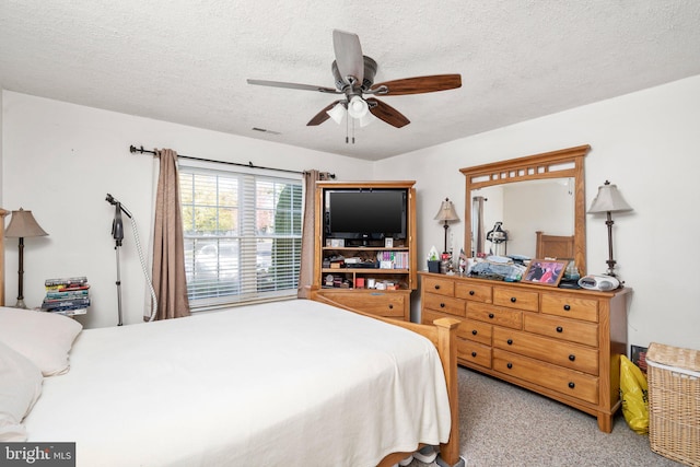 bedroom featuring ceiling fan, light colored carpet, and a textured ceiling