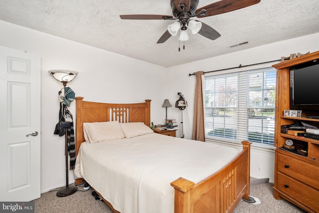 bedroom with a textured ceiling, ceiling fan, and light carpet