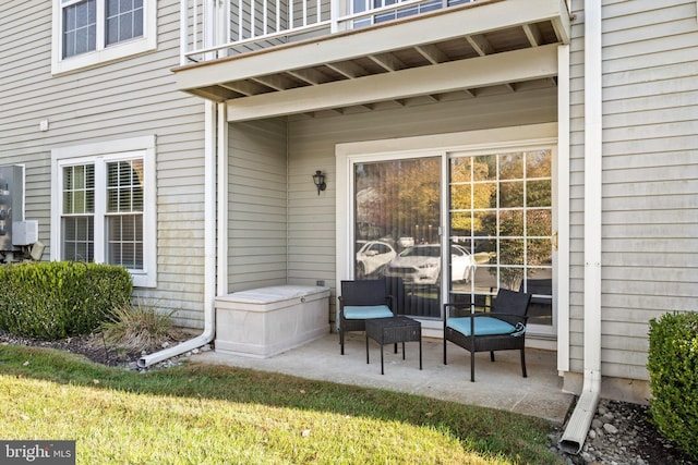 entrance to property with a balcony, a yard, and a patio