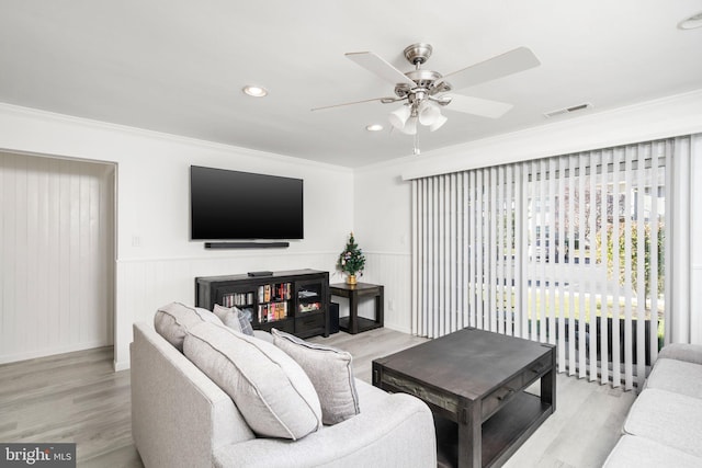 living room featuring light wood-type flooring, ceiling fan, and ornamental molding