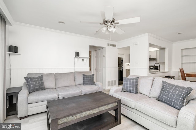 living room featuring ceiling fan, sink, crown molding, and light hardwood / wood-style flooring