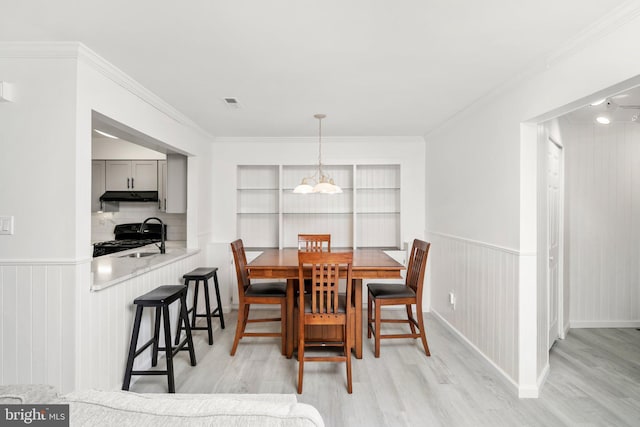 dining room featuring light hardwood / wood-style floors, sink, and crown molding