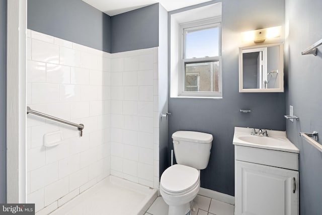 bathroom with tile patterned flooring, vanity, toilet, and a tile shower