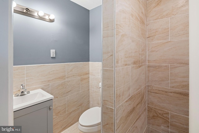 bathroom with vanity, toilet, and tile walls