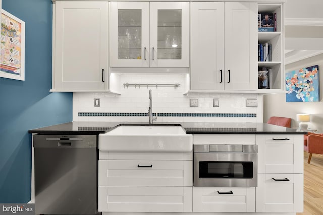 kitchen with sink, decorative backsplash, dark stone countertops, appliances with stainless steel finishes, and white cabinetry