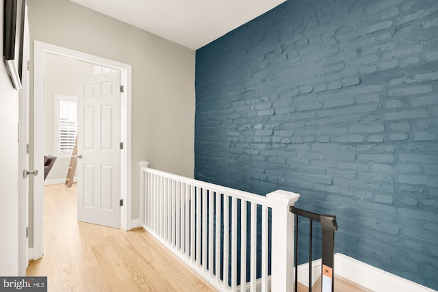 corridor featuring light hardwood / wood-style floors and brick wall