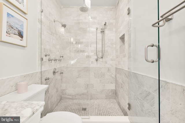 bathroom featuring an enclosed shower, toilet, and tile walls