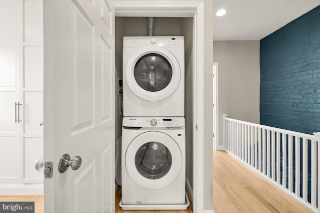 laundry area with light wood-type flooring and stacked washing maching and dryer