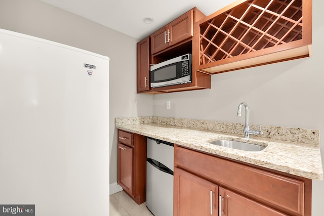 kitchen with light stone countertops, light tile patterned floors, white refrigerator, and sink