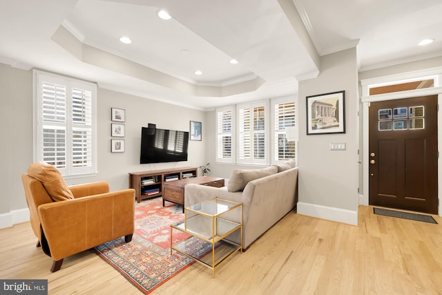 living room featuring a tray ceiling, crown molding, and light hardwood / wood-style flooring