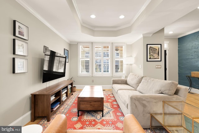 living room with wood-type flooring, a raised ceiling, and ornamental molding