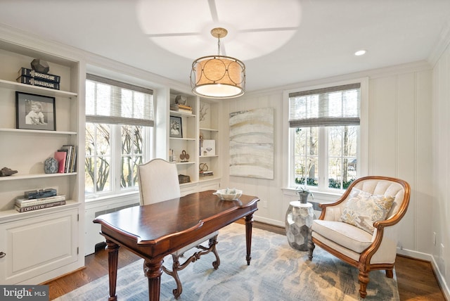 office space featuring crown molding, built in shelves, and dark wood-style flooring