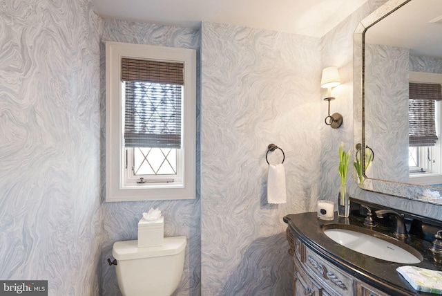 bathroom featuring plenty of natural light, toilet, and wallpapered walls