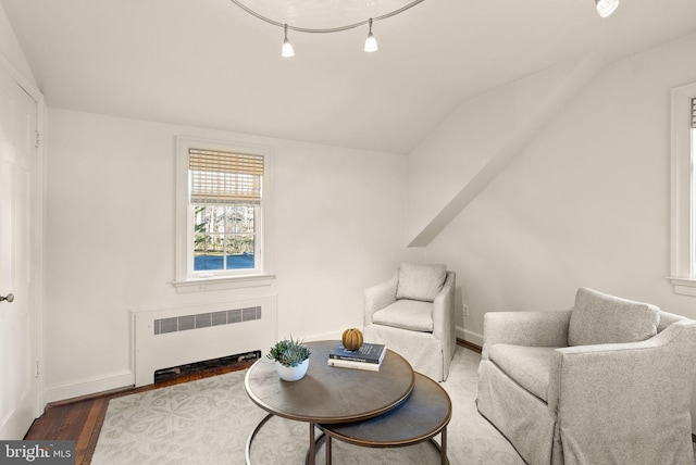 living area with lofted ceiling, radiator heating unit, wood finished floors, and baseboards