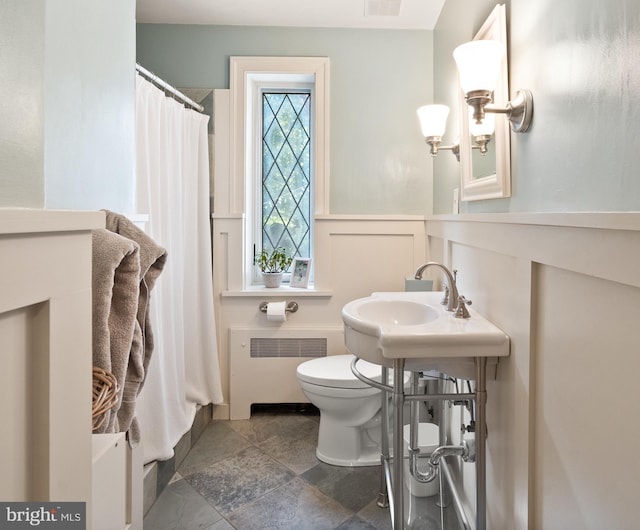 full bath featuring a decorative wall, toilet, radiator heating unit, wainscoting, and a shower with curtain