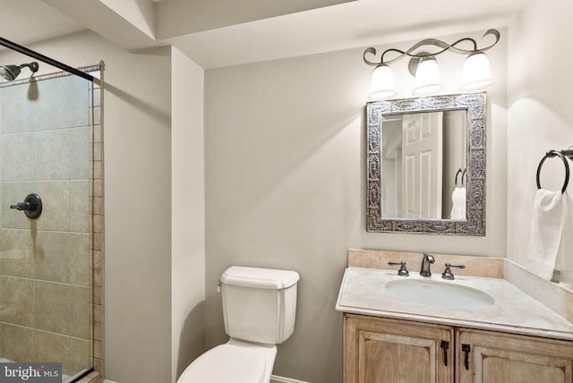 bathroom with tiled shower, vanity, and toilet