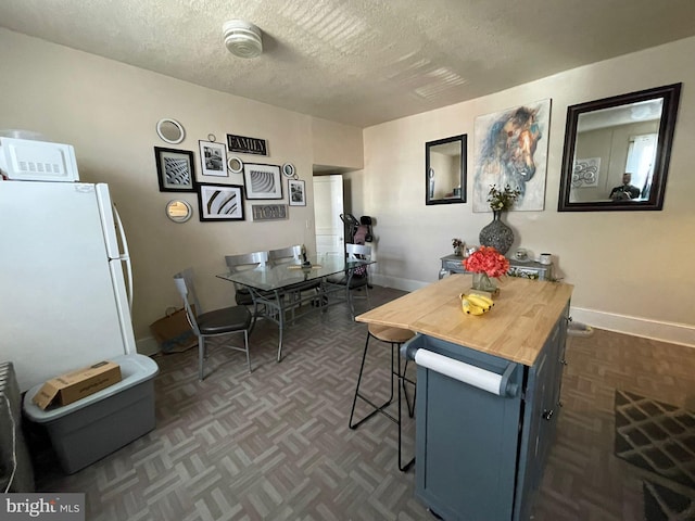 dining area featuring dark parquet flooring and a textured ceiling