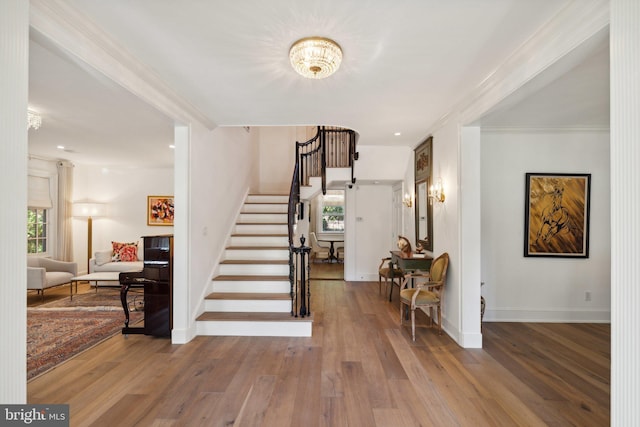 stairway featuring hardwood / wood-style floors, ornamental molding, and a notable chandelier