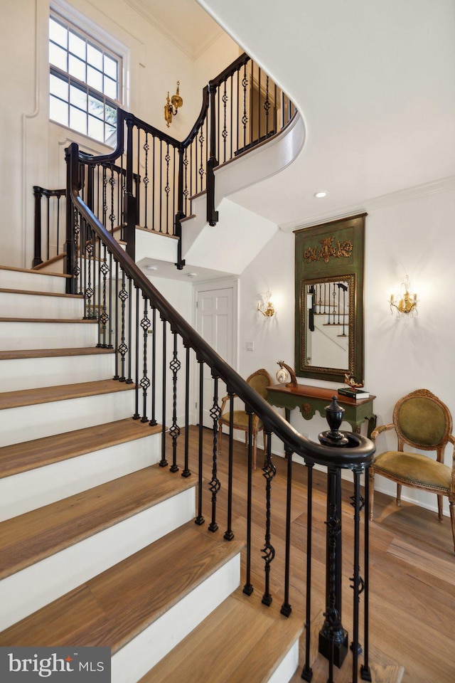 staircase with crown molding and hardwood / wood-style floors