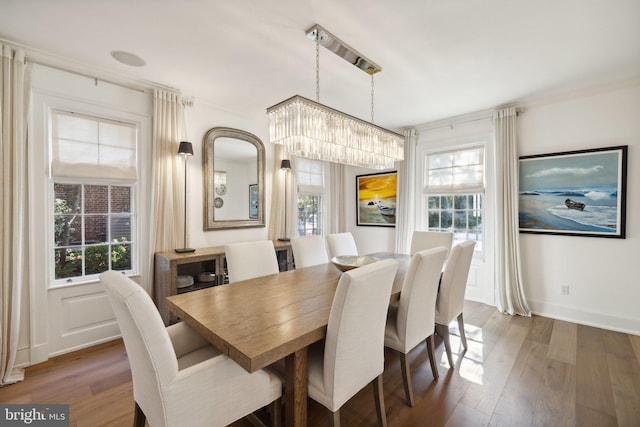 dining room featuring an inviting chandelier, dark hardwood / wood-style flooring, ornamental molding, and plenty of natural light