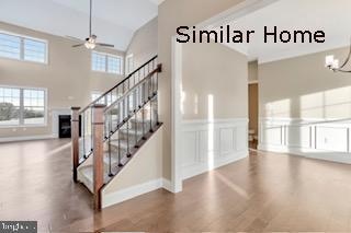 staircase with hardwood / wood-style floors, ceiling fan with notable chandelier, and a high ceiling