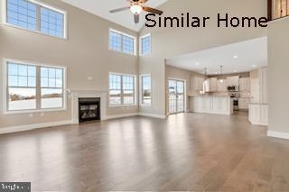 unfurnished living room featuring hardwood / wood-style floors, a towering ceiling, a wealth of natural light, and ceiling fan