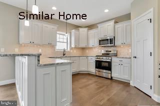 kitchen featuring appliances with stainless steel finishes, white cabinetry, and pendant lighting