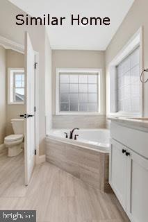 bathroom featuring tiled bath, toilet, vanity, and hardwood / wood-style flooring