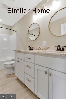 full bathroom featuring wood-type flooring, vanity, toilet, and tub / shower combination