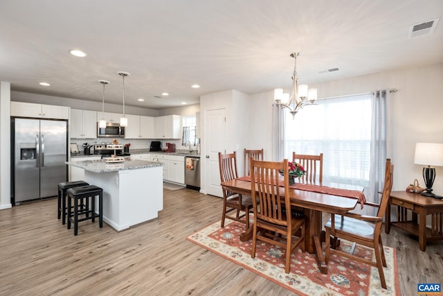 dining room featuring a notable chandelier, light wood-type flooring, and sink