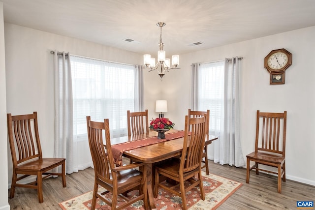 dining area featuring plenty of natural light, an inviting chandelier, and light hardwood / wood-style flooring