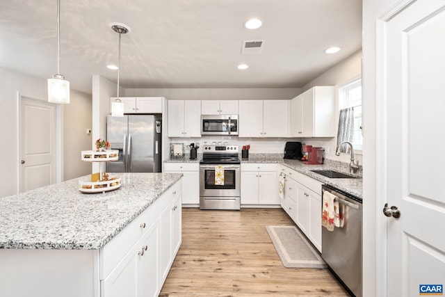 kitchen with a center island, sink, decorative light fixtures, white cabinetry, and stainless steel appliances