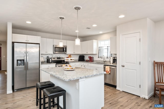 kitchen with white cabinets, a kitchen island, sink, and appliances with stainless steel finishes