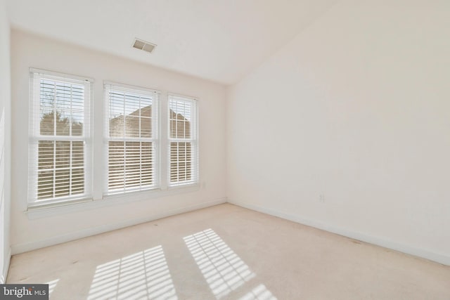 carpeted empty room with vaulted ceiling