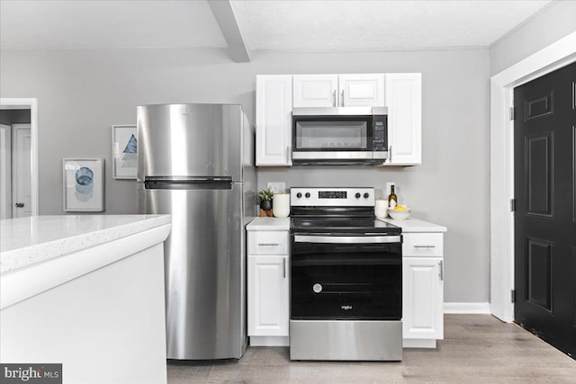 kitchen featuring white cabinetry, light stone counters, light hardwood / wood-style flooring, beamed ceiling, and appliances with stainless steel finishes