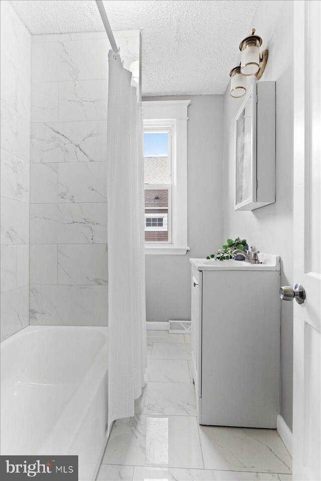 bathroom featuring shower / bath combo and a textured ceiling