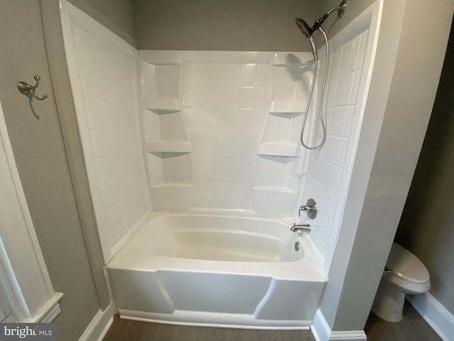 bathroom featuring hardwood / wood-style flooring, toilet, and washtub / shower combination