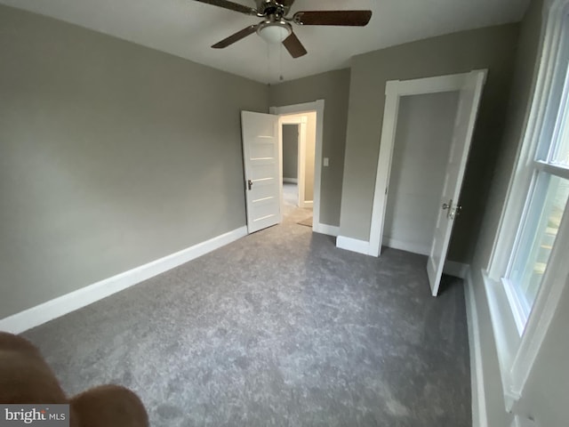 unfurnished bedroom with dark carpet and ceiling fan