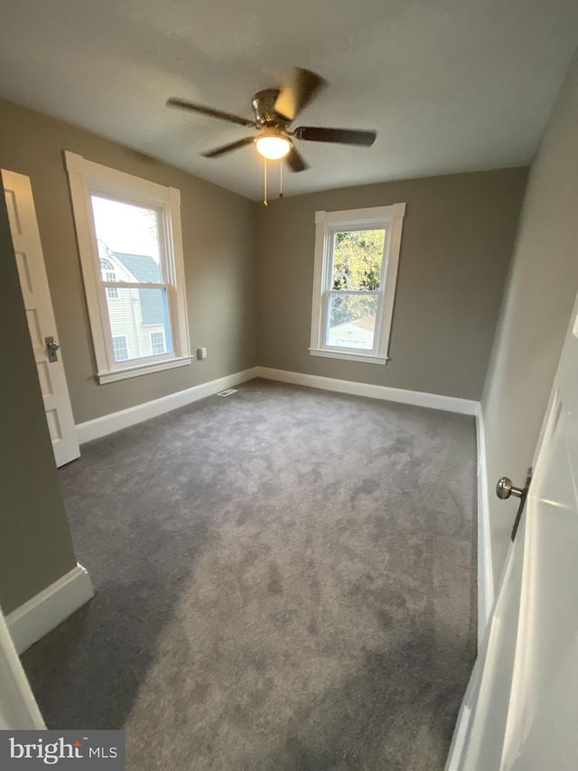 unfurnished room with ceiling fan and dark colored carpet