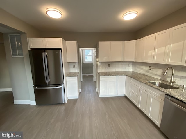 kitchen featuring backsplash, sink, light stone counters, white cabinetry, and stainless steel appliances