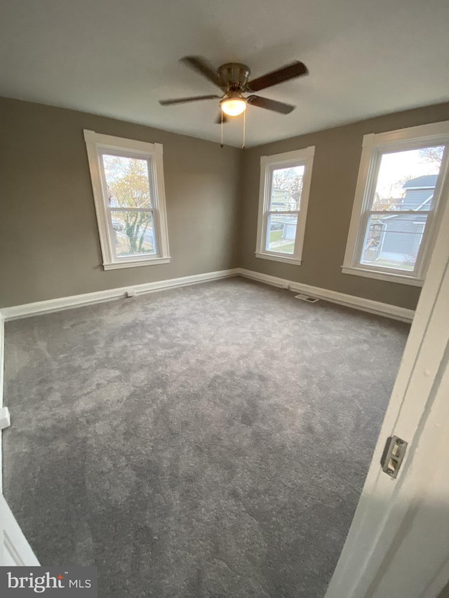 carpeted empty room with a wealth of natural light and ceiling fan