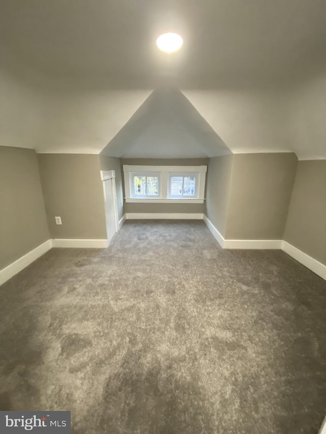 bonus room featuring dark colored carpet and lofted ceiling