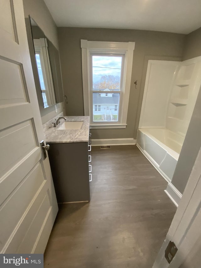 bathroom with hardwood / wood-style flooring, vanity, and shower / bathing tub combination