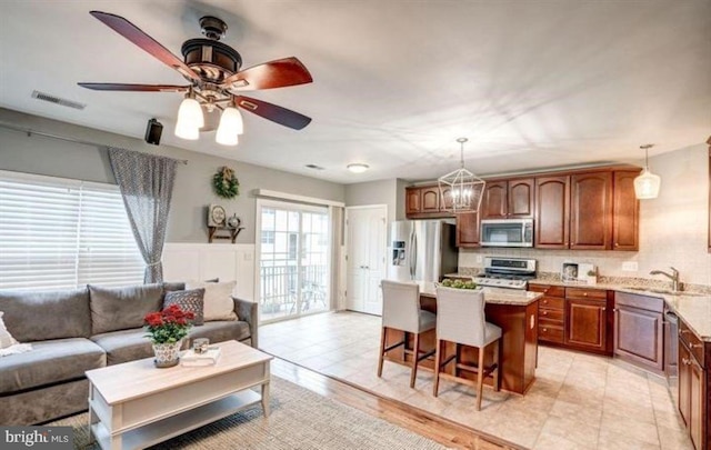 kitchen featuring sink, hanging light fixtures, light hardwood / wood-style floors, a kitchen island, and stainless steel appliances