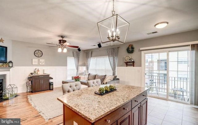 kitchen with hanging light fixtures, a kitchen island, a healthy amount of sunlight, and ceiling fan with notable chandelier