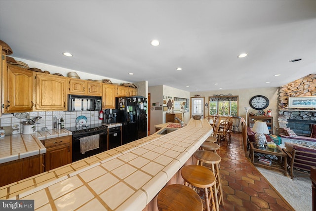 66 Pelican Dr, Avalon, NJ 08202 - kitchen featuring black appliances, tile counters, a sink, backsplash, and a kitchen bar