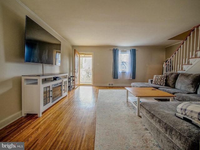 living area with visible vents, crown molding, baseboards, stairway, and wood finished floors