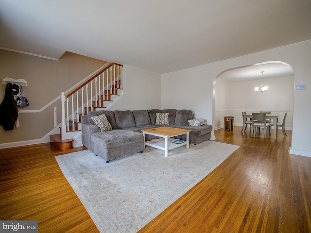 living room featuring stairway, arched walkways, baseboards, and wood finished floors